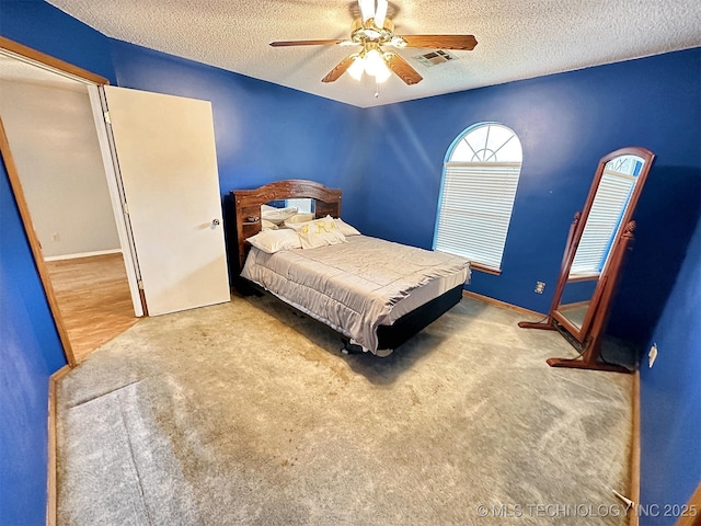 carpeted bedroom with ceiling fan and a textured ceiling