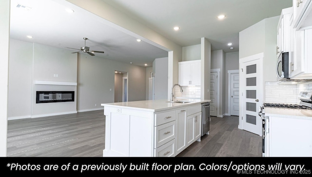 kitchen featuring an island with sink, wood-type flooring, white cabinets, ceiling fan, and stainless steel appliances