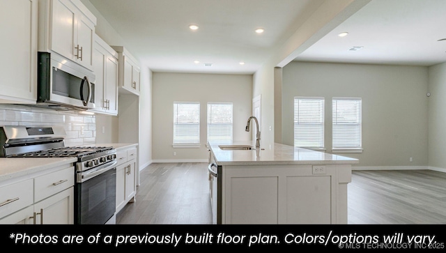 kitchen featuring stainless steel appliances, sink, an island with sink, and white cabinets