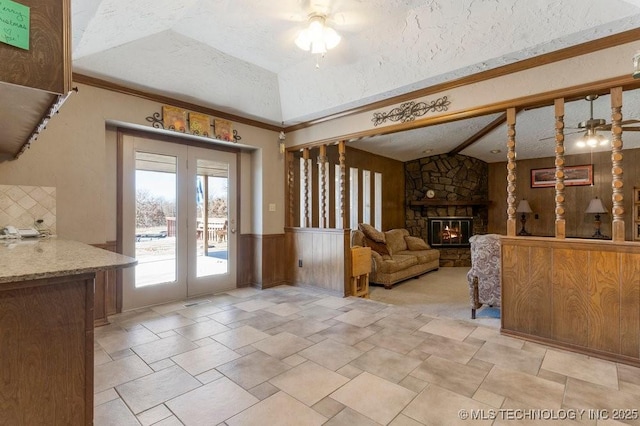 interior space featuring ceiling fan, a fireplace, a textured ceiling, vaulted ceiling, and french doors