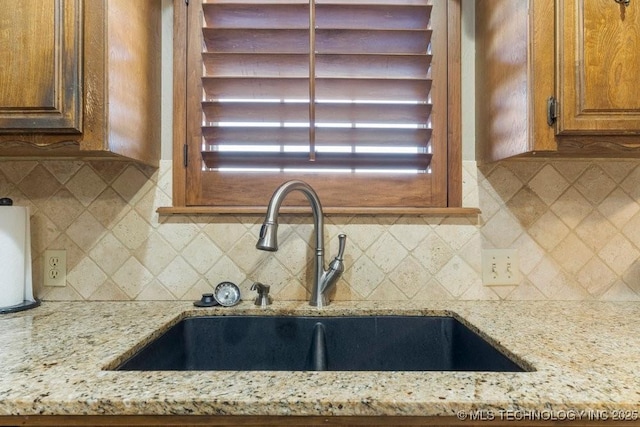 kitchen with tasteful backsplash, sink, and light stone counters