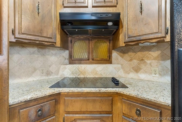 kitchen with light stone counters, black electric stovetop, ventilation hood, and decorative backsplash