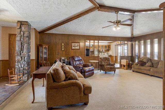 living room with vaulted ceiling with beams, wooden walls, a textured ceiling, and carpet flooring