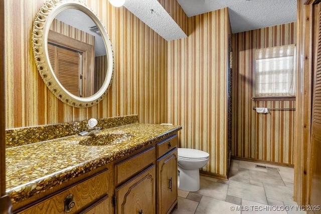 bathroom featuring vanity, toilet, and a textured ceiling