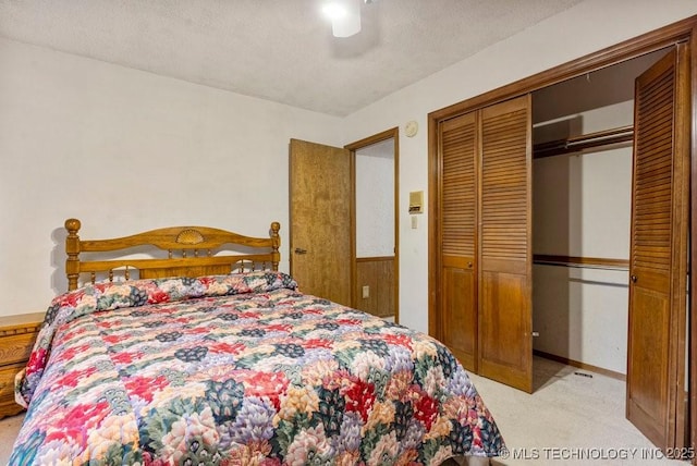 carpeted bedroom with a textured ceiling, ceiling fan, and a closet