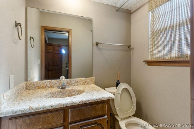 bathroom featuring vanity, plenty of natural light, and toilet