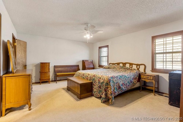 bedroom featuring a textured ceiling, light colored carpet, and ceiling fan