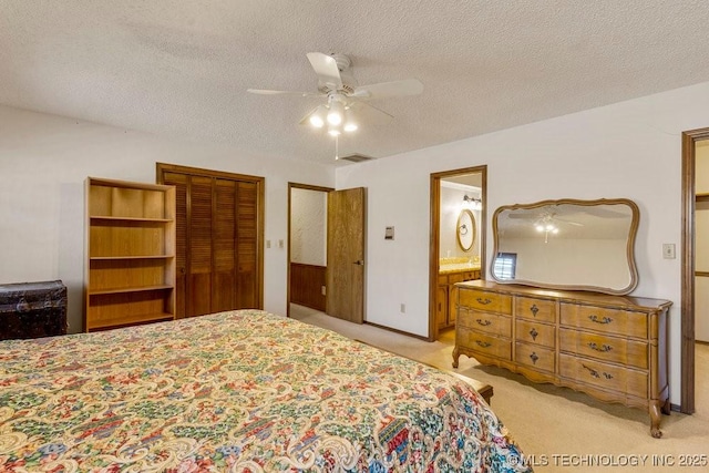 bedroom with light carpet, ceiling fan, a textured ceiling, and ensuite bathroom