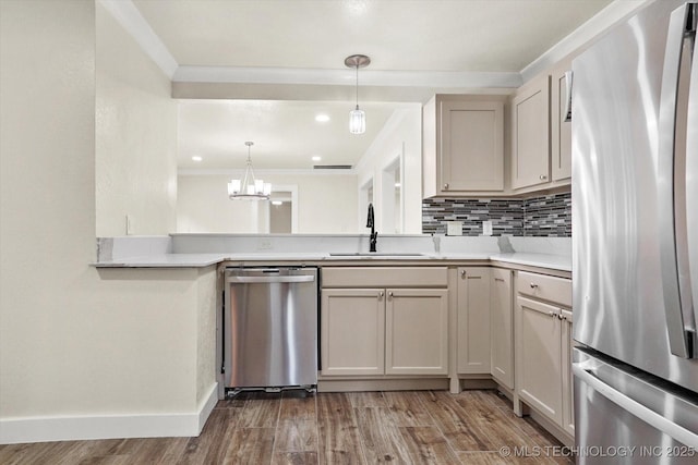 kitchen with sink, hardwood / wood-style flooring, appliances with stainless steel finishes, tasteful backsplash, and decorative light fixtures