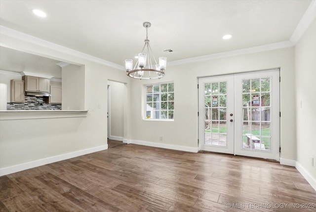 unfurnished dining area with an inviting chandelier, dark wood-type flooring, ornamental molding, and french doors