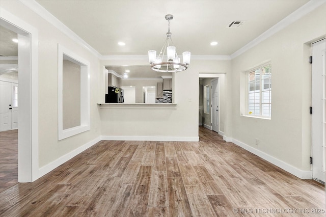 unfurnished dining area featuring ornamental molding, a notable chandelier, and light hardwood / wood-style floors