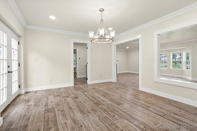 empty room featuring ornamental molding, an inviting chandelier, and light wood-type flooring