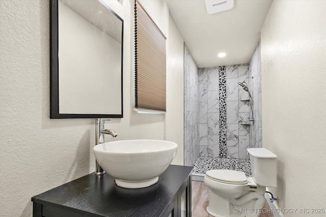 bathroom with sink, toilet, and tiled shower