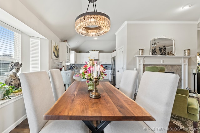 dining room with crown molding, a tile fireplace, and a notable chandelier