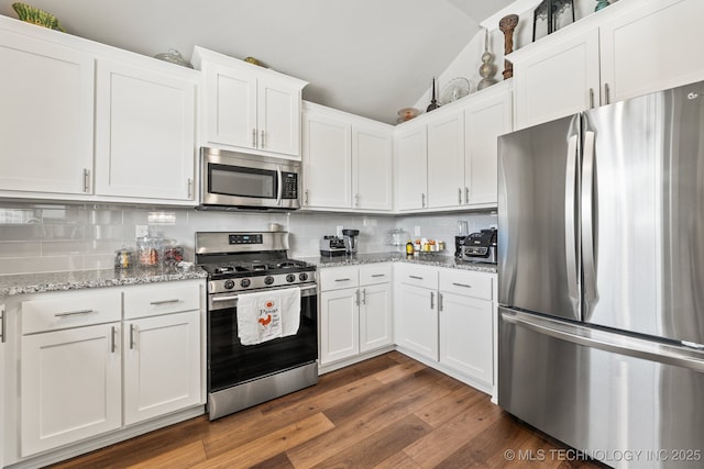 kitchen with lofted ceiling, stainless steel appliances, light stone counters, white cabinets, and decorative backsplash