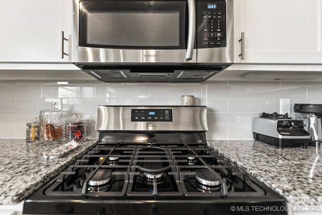 details with white cabinetry, tasteful backsplash, stainless steel appliances, and light stone counters