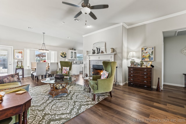 living room featuring crown molding, dark wood-type flooring, ceiling fan, and a fireplace