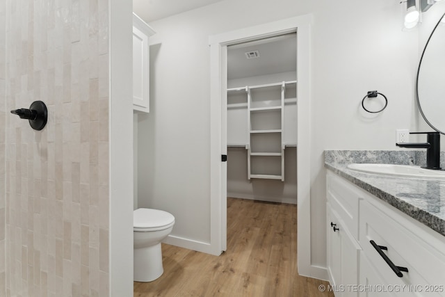 203 W Monroe Ave, Mcalester, OK 74501 - full bath with wood finished floors, vanity, toilet, a tile shower, and a walk in closet