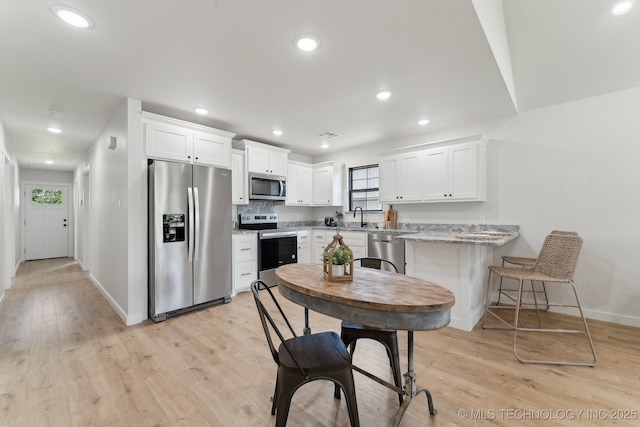 203 W Monroe Ave, Mcalester, OK 74501 - kitchen featuring stainless steel appliances, baseboards, white cabinets, light wood-type flooring, and a sink