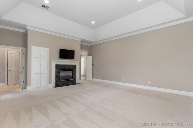 unfurnished living room featuring ornamental molding, a high end fireplace, light colored carpet, and a raised ceiling