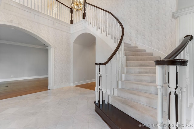 stairs with crown molding and a towering ceiling