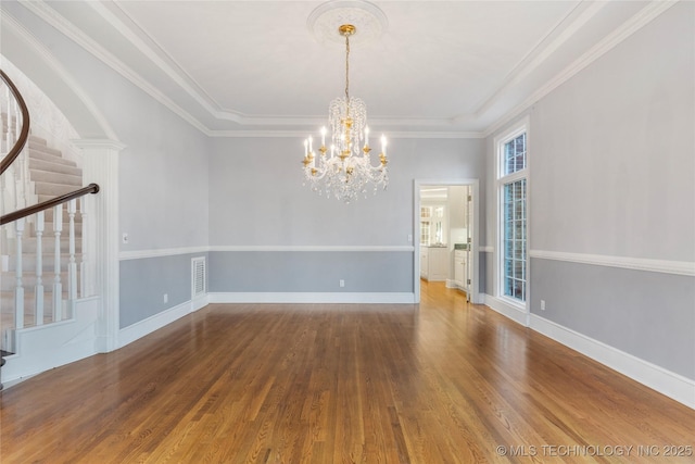 empty room featuring an inviting chandelier, crown molding, and wood-type flooring