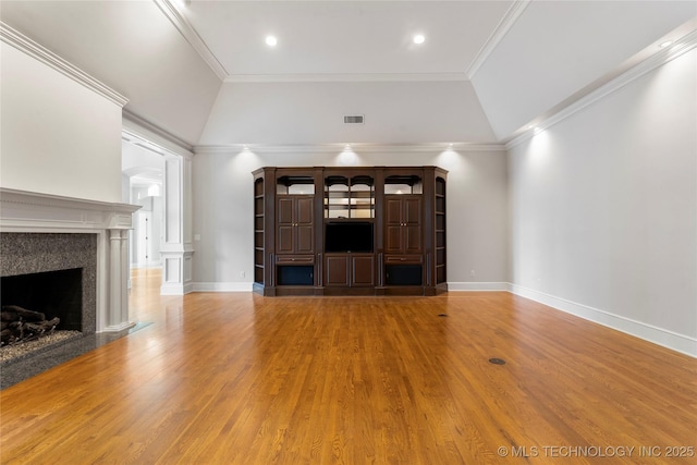 unfurnished living room with hardwood / wood-style floors, a towering ceiling, a fireplace, and ornamental molding