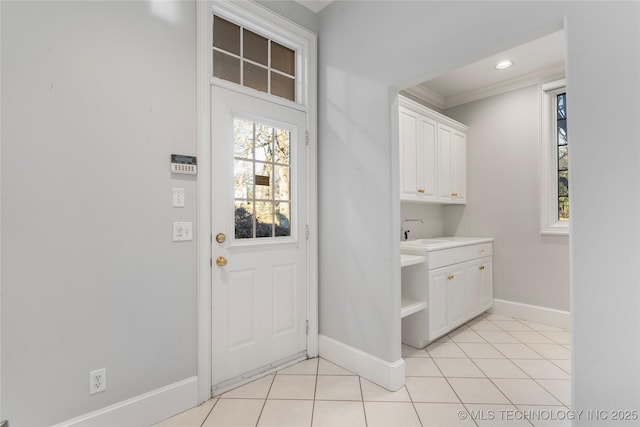 clothes washing area with light tile patterned flooring, crown molding, and sink