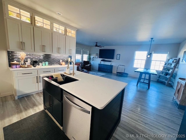 kitchen with decorative light fixtures, white cabinets, a kitchen island with sink, stainless steel dishwasher, and plenty of natural light