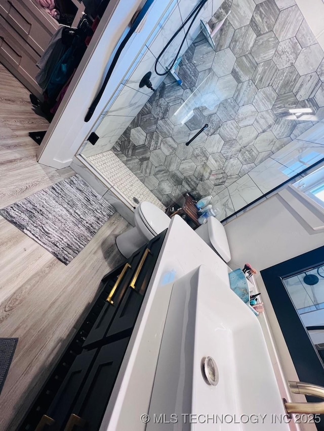 bathroom with walk in shower, toilet, and hardwood / wood-style flooring