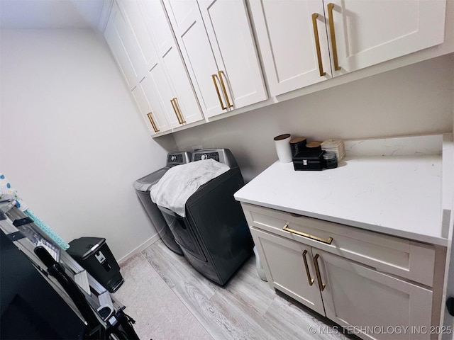 laundry area with cabinets, light hardwood / wood-style floors, and washing machine and dryer