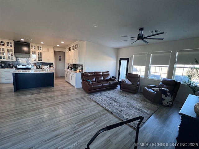 living room featuring ceiling fan, sink, and light hardwood / wood-style floors