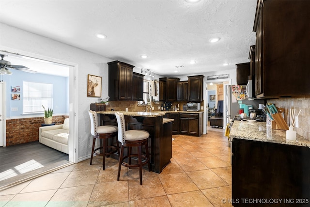 kitchen featuring light stone counters, a kitchen bar, kitchen peninsula, and light tile patterned flooring