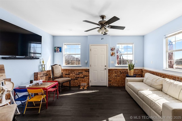 living room featuring ceiling fan, brick wall, and dark hardwood / wood-style flooring