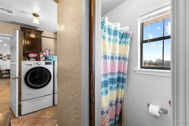 clothes washing area with cabinets, washer / clothes dryer, and light tile patterned floors