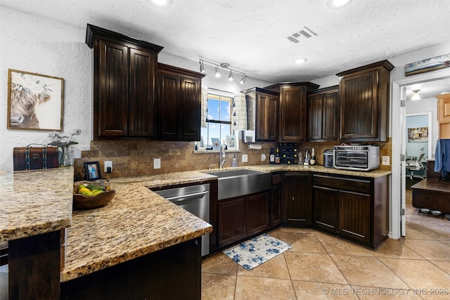 kitchen with sink, light tile patterned floors, backsplash, light stone counters, and stainless steel dishwasher