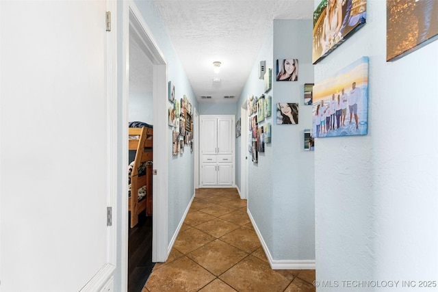 hallway with tile patterned flooring and a textured ceiling