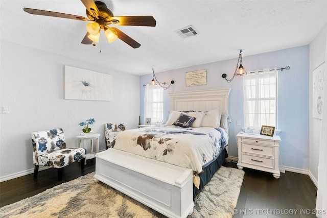 bedroom featuring ceiling fan, dark hardwood / wood-style flooring, and multiple windows