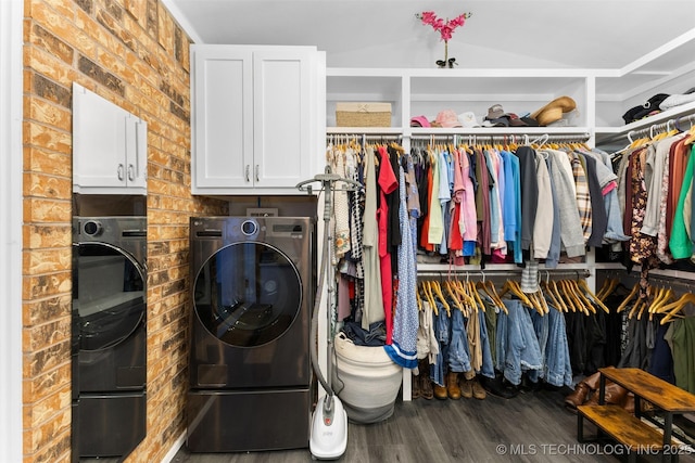 laundry area featuring dark wood-type flooring, cabinets, brick wall, and separate washer and dryer