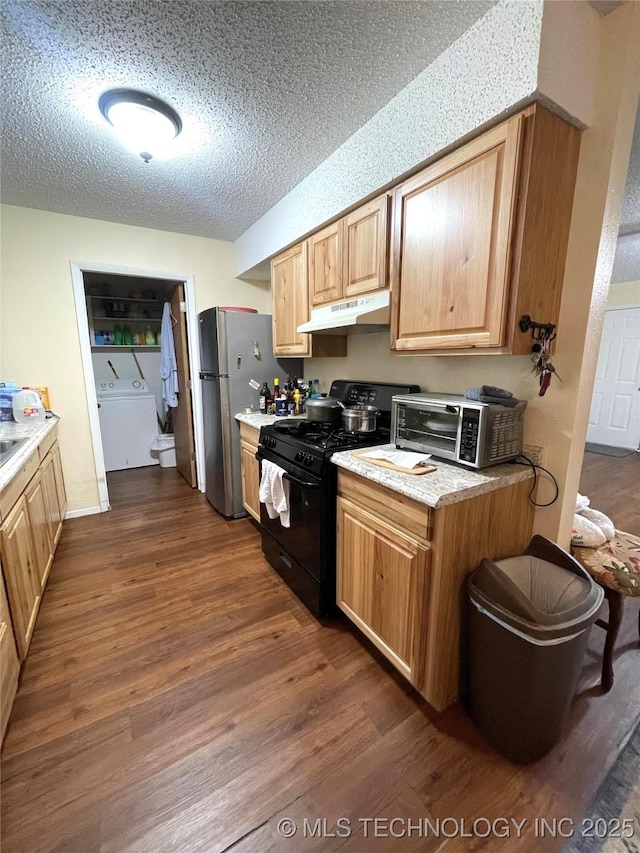 kitchen with stainless steel refrigerator, washer / clothes dryer, gas stove, dark wood-type flooring, and a textured ceiling