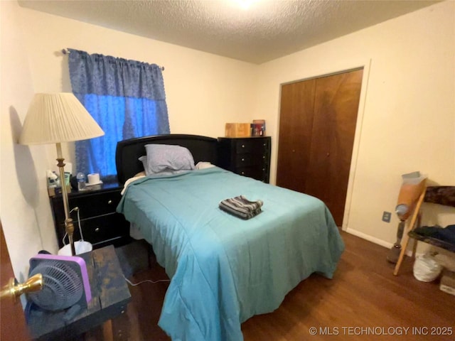 bedroom featuring dark hardwood / wood-style floors, a textured ceiling, and a closet