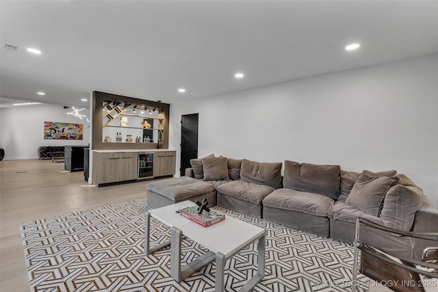 living room featuring bar, beverage cooler, and light wood-type flooring