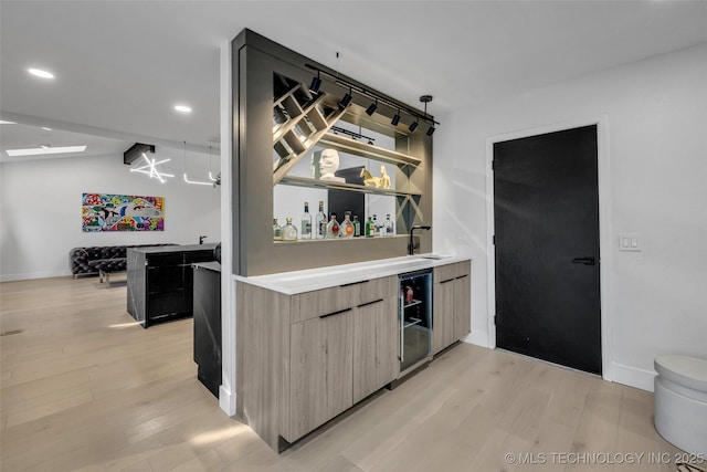 bar with wine cooler, lofted ceiling, sink, and light hardwood / wood-style floors