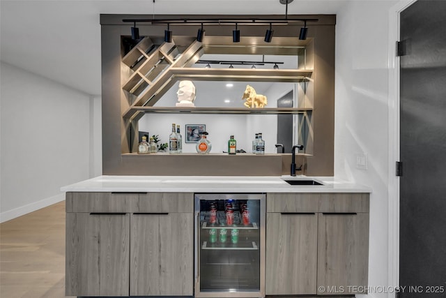 bar featuring pendant lighting, sink, wine cooler, track lighting, and light wood-type flooring