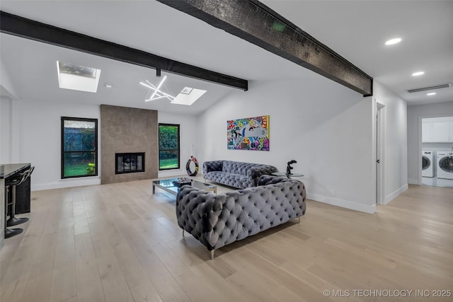 living room featuring a fireplace, lofted ceiling with beams, independent washer and dryer, and light wood-type flooring