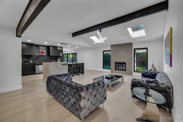 living room featuring a wealth of natural light, lofted ceiling with beams, and light hardwood / wood-style floors