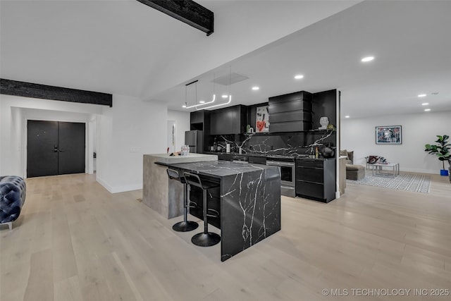 kitchen with premium range hood, a kitchen island, appliances with stainless steel finishes, a kitchen bar, and hanging light fixtures