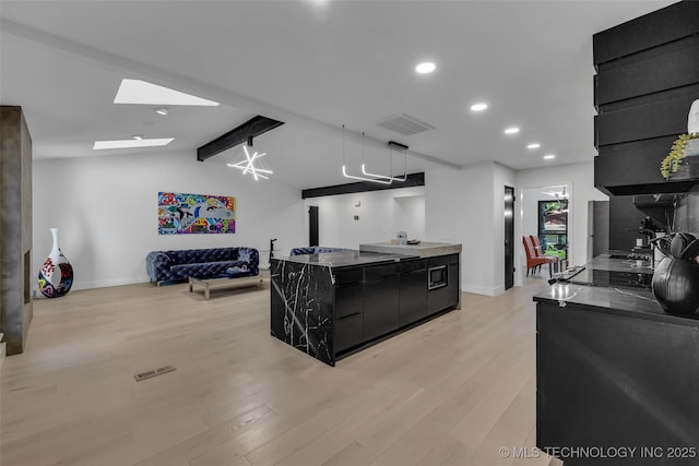 kitchen featuring a center island, vaulted ceiling with skylight, black electric cooktop, and light hardwood / wood-style flooring