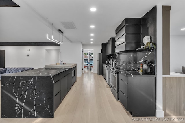 kitchen featuring premium range hood, tasteful backsplash, light hardwood / wood-style flooring, dark stone countertops, and appliances with stainless steel finishes