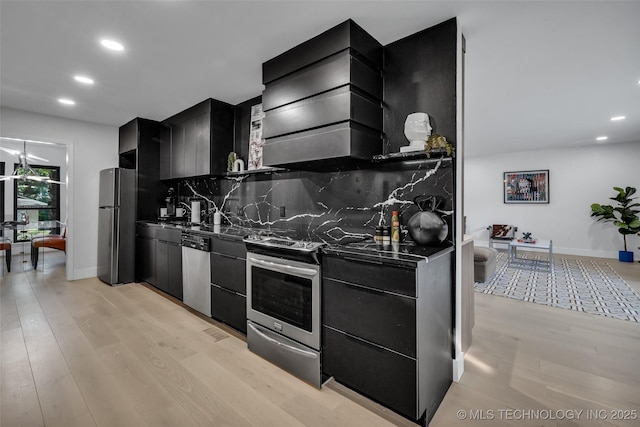 kitchen featuring premium range hood, appliances with stainless steel finishes, light hardwood / wood-style floors, and decorative backsplash